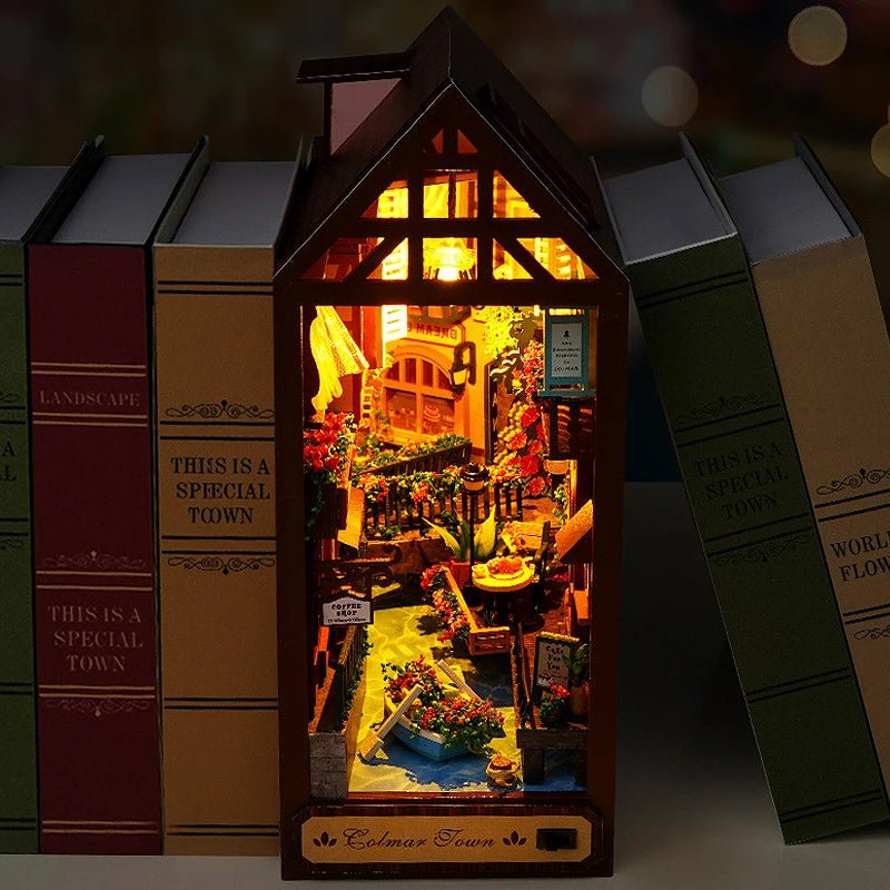 European street book nook shelf insert glowing at night – cobblestone alley with warm amber LED windows
